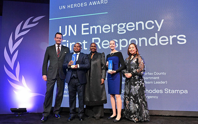 UNDAC and INSARAG Focal Points in front of screen, holding the UN Heroes Award